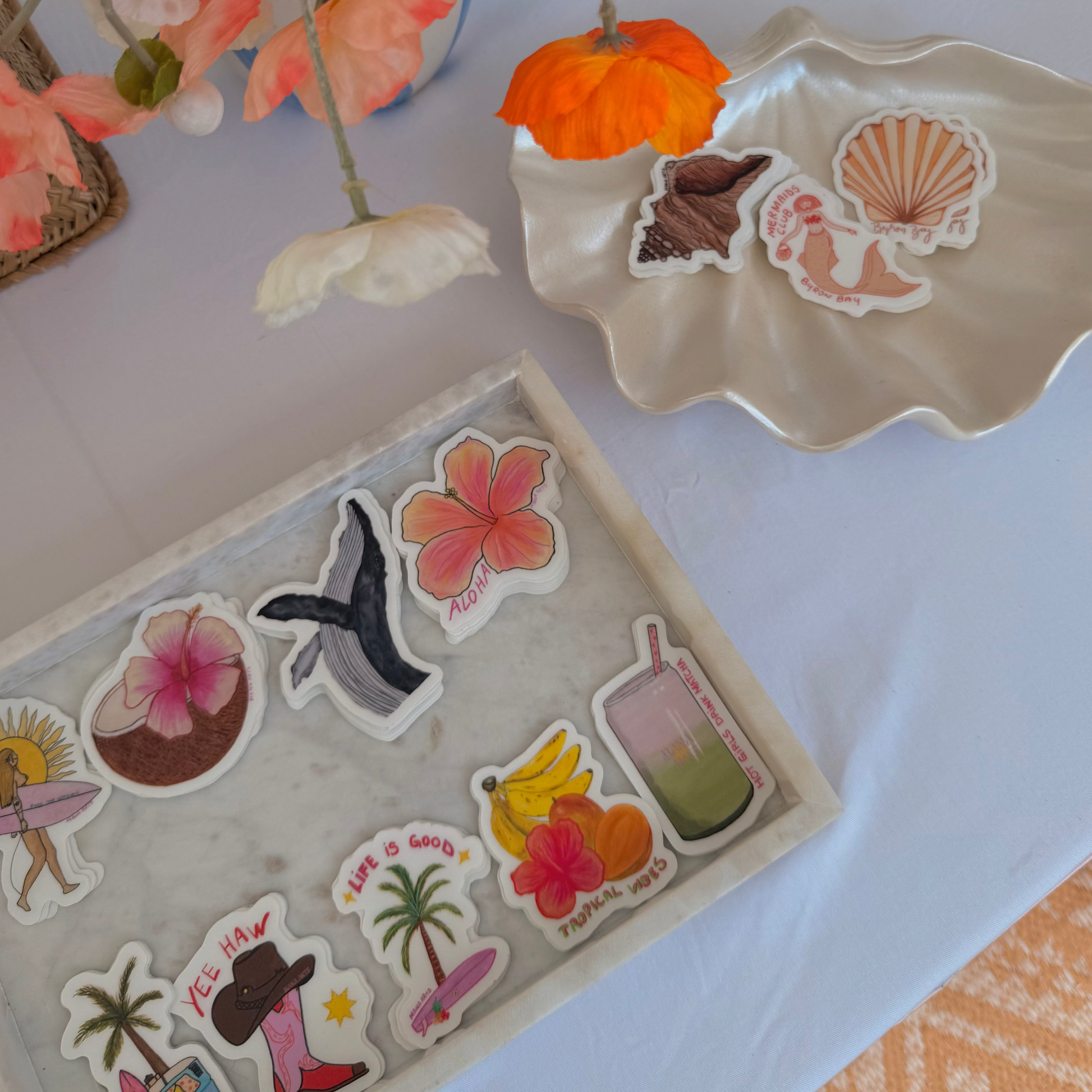 Set of beach-themed stickers on a tray with flowers in the background